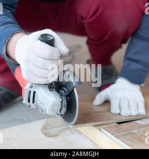 repair and decoration. a man cuts ceramic tiles with a grinder. Stock Photo