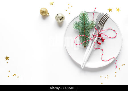 Christmas Table Setting with fir branch and red ornaments on white, flat lay, copy space. Christmas dinner, party design, concept - table setting with Stock Photo
