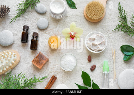 Natural Skin Care and Spa Set on white soft towel background with natural cosmetic products, flower, green leaves, candle and zen like stones. Relax c Stock Photo