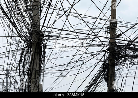 A chaotic mess of telecommunication and internet cables across a southest asian sky Stock Photo