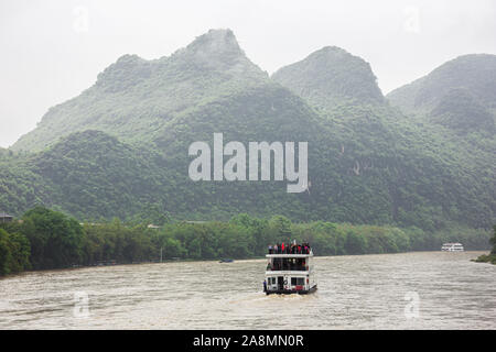 Editorial: GUILIN, GUANGXI, CHINA, April 19, 2019 - Following a river boat navigating on the Li River near Guilin Stock Photo