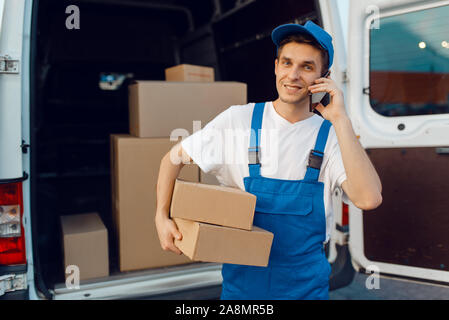 Deliveryman in uniform holds parcel and phone Stock Photo