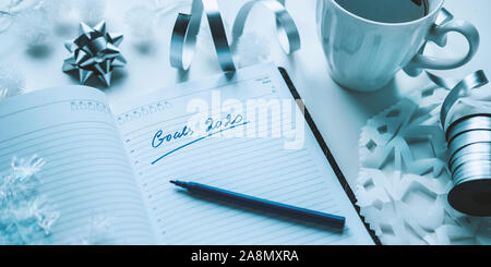 2020 goals written on a diary with light, hot coffe or tea and decoration. Happy New Year and motivation consept background Stock Photo