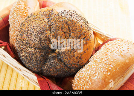 Poppy seed and sesame seed Kaiser Rolls in a light colored wood basket.  Shot in natural sunlight. Stock Photo