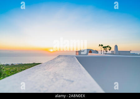 Defocused effect of early morning view along parapet top surface into horizon and Santorini sunrise as travel or nature background. Stock Photo