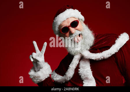 Waist up portrait of funky Santa wearing sunglasses and smiling at camera ready to enjoy Christmas party, copy space Stock Photo