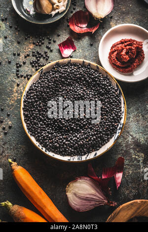 Close up black lentils in bowl with ingredients for delicious cooking.  Top view. Copy space. Healthy food. Protein rich vegan foods. Plant based prot Stock Photo
