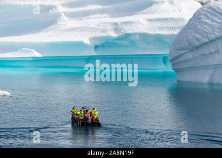 Tourists sailing in a small boat close to large Icebergs from Tunulliarfik fjord in summer. Narsaq, Kujalleq, South Greenland Stock Photo