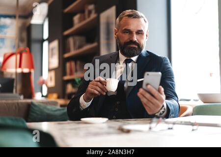 Business man in formal clothing using mobile phone. Serious businessman using smartphone at work Stock Photo