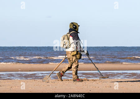 Metal detecting on the beach at Southport, UK. 10th November 2019.  After a week of continuous rain, the sunshine finally breaks through a metal detectorist hunts for hidden treasures on a cold crisp day on Southport beach in Merseyside.  Credit: Cernan Elias/Alamy Live News