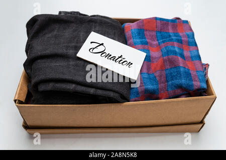 Donation concept. Donation box with donation clothes on a white background. Charity. Helping needy people. Stock Photo