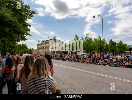 Lund, Sweden - May 19, 2018: The cobblestoned road next to the train station is bordered with people waiting for the parade Lundakarnevalen to begin Stock Photo