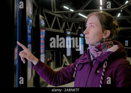 Woman using interactive touchscreen display of electronic multimedia kiosk Stock Photo