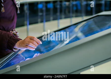 Woman using multimedia touchscreen display of interactive kiosk Stock Photo