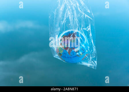 the world or earth model in a transparency plastic bag for environmental pollution planet protection concept with blue sky background Stock Photo