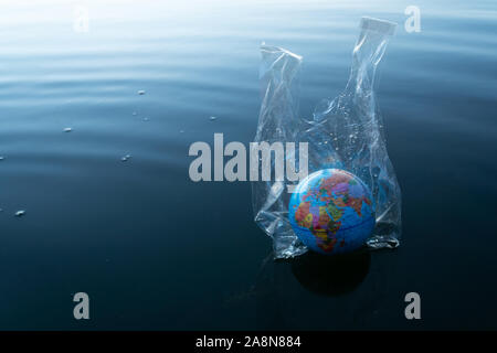 the world or earth model in a transparency plastic bag floating in dark blue marine ocean water for environmental pollution planet protection concept Stock Photo