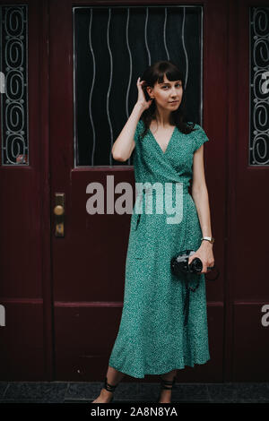 elegant woman wearing a green dress is holding an old film camera in her hands Stock Photo