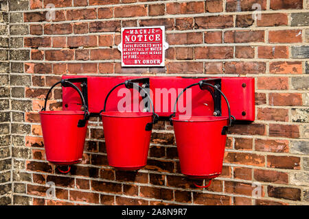 Three fire buckets hanging on the wall. Stock Photo
