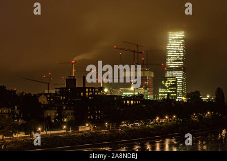 Dramatic cityscape of a big construction site on a rainy and foggy night in Basel, with the Roche Tower, Switzerland. Stock Photo