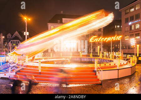 The Enterprise amusement ride in motion with the wheel spinning very fast, Travelling funfair Herbst Messe at night in Basel downtown, Switzerland. Stock Photo