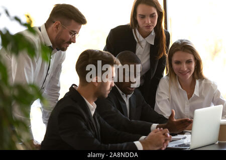 Multiethnic colleagues discuss project work together at laptop Stock Photo