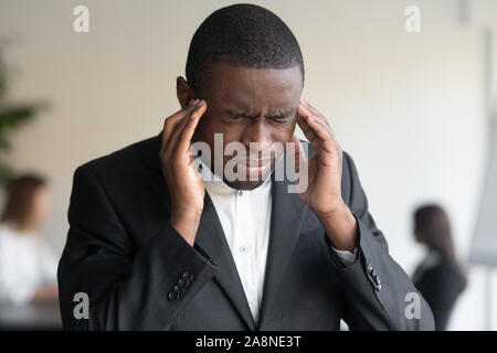 Close up of stressed biracial businessman suffering from headache Stock Photo