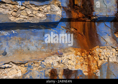 Coastal damaged grunge wall abstract background from old waterfront, weathered by the sea with different colors of rust, dirty blue paint damaged plas Stock Photo