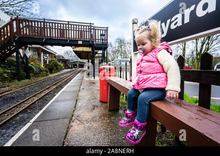 A little girl sits by the famous miniature ride along railway museum, popular with families and children, Staffordshire's tourist attraction Stock Photo