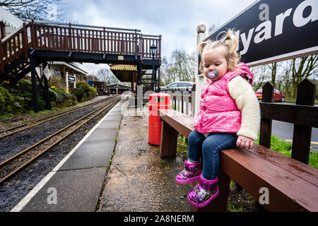 A little girl sits by the famous miniature ride along railway museum, popular with families and children, Staffordshire's tourist attraction Stock Photo