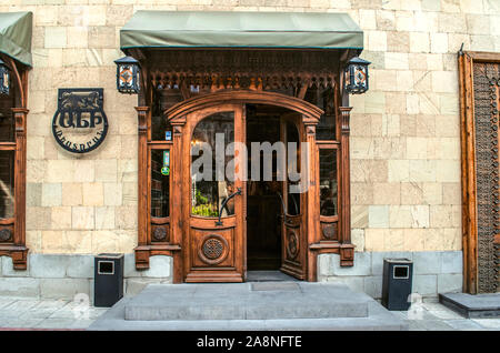 Gyumri,Armenia,05 September,2019: Entrance to the restaurant is through a double wooden door decorated with carved ornaments and a cornice in a buildi Stock Photo