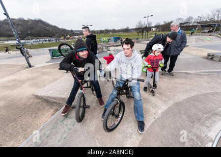 A group of BMX riders chat at Plaza skate park whilst sitting on their BMX's, having a rest Stock Photo