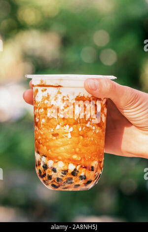 Woman hand holding iced milk bubble tea with tapioca pearls and caramel Stock Photo