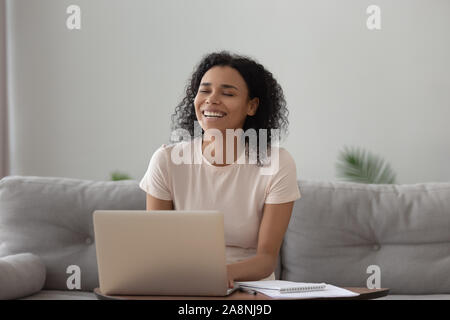 Smiling African American woman using laptop, chatting online, having fun