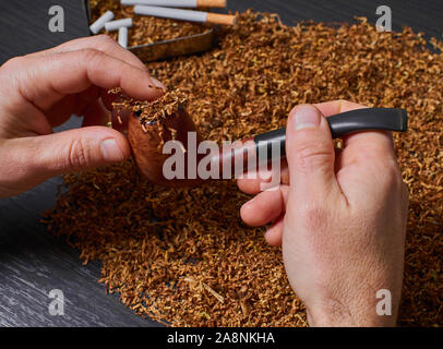man stuffs a pipe with tobacco, hands closeup Stock Photo