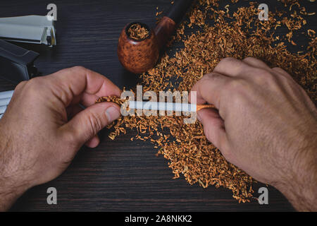 man makes a cigarette with rolling machine, hands closeup Stock Photo