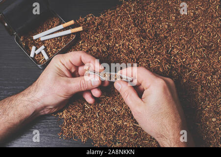 man makes a cigarette tobacco roll in tissue paper Stock Photo