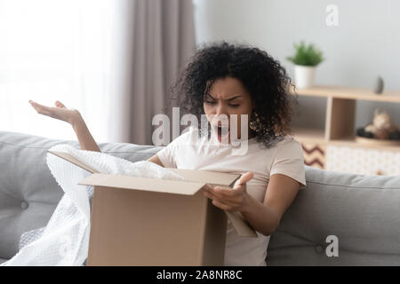 Unhappy angry African American woman client dissatisfied by parcel Stock Photo