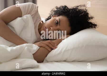 Unhappy African American woman suffering from insomnia, lying in bed Stock Photo