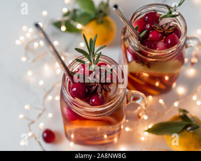 Winter sangria in mason jars with metal straws on christmas holiday background. Decorated fruit slice, cranberry and rosemary. Copy space for text or design. Horizontal. Decoration lighting chain Stock Photo