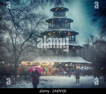 Munich, Germany - Christmas market at Chinese Tower in Englischer Garten and snowfall Stock Photo