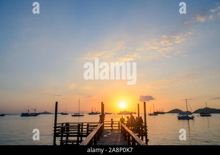Tourists enjoy the sunset at the wooden pier beach, on Labuan Bajo, West Manggarai, Flores Island, East Nusa Tenggara, Indonesia Stock Photo