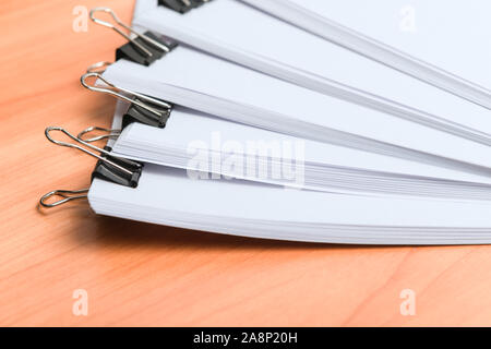 Many printed paper documents with black clips on wooden table Stock Photo