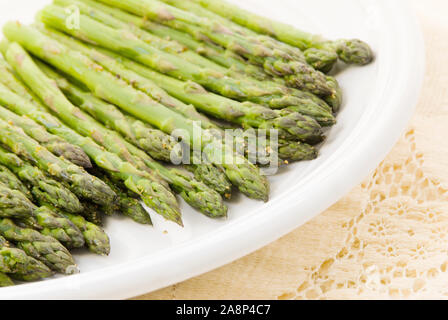 Homemade organic roasted asparagus spears sprinkled with salt, pepper, garlic and other herbs. Shot in natural light. Selective focusing. Stock Photo