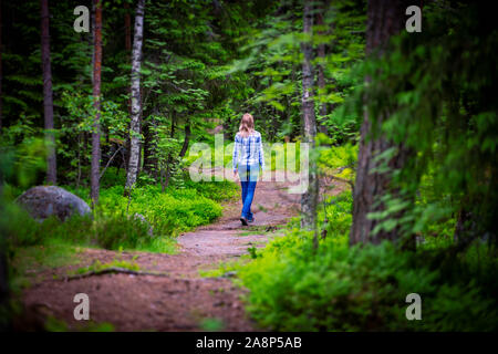 Woman on curved forest road in summer. Trees on sides of road Stock Photo