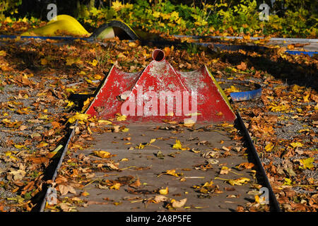 Old untended miniature golf course with very chipped red paint covered in yellow autumn leaves Stock Photo