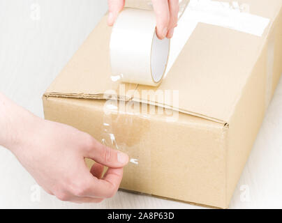 Hands with roll adhesive tape on a cardbox Stock Photo