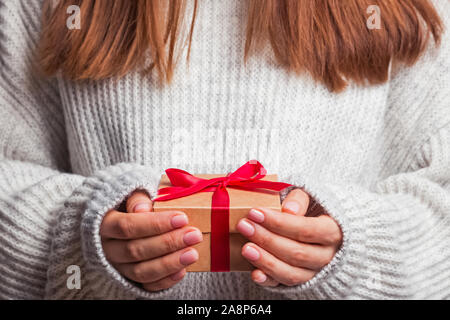 Female hands holding gift box with red ribbon close-up. Stock Photo