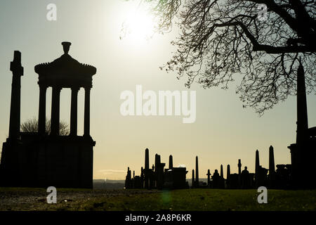 The sunny autumn day of the Victorian cemetery Necropolis in United Kingdom photographed from afar with the sun backlight. Black cemetery silhouette Stock Photo