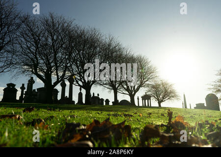 The sunny autumn day of the Victorian cemetery Necropolis in United Kingdom photographed from afar with the sun backlight. Black cemetery silhouette Stock Photo