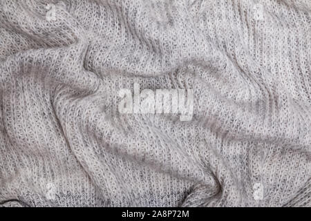 Texture of warm knitted woolen cloth, sweater or scarf of gray color Stock Photo